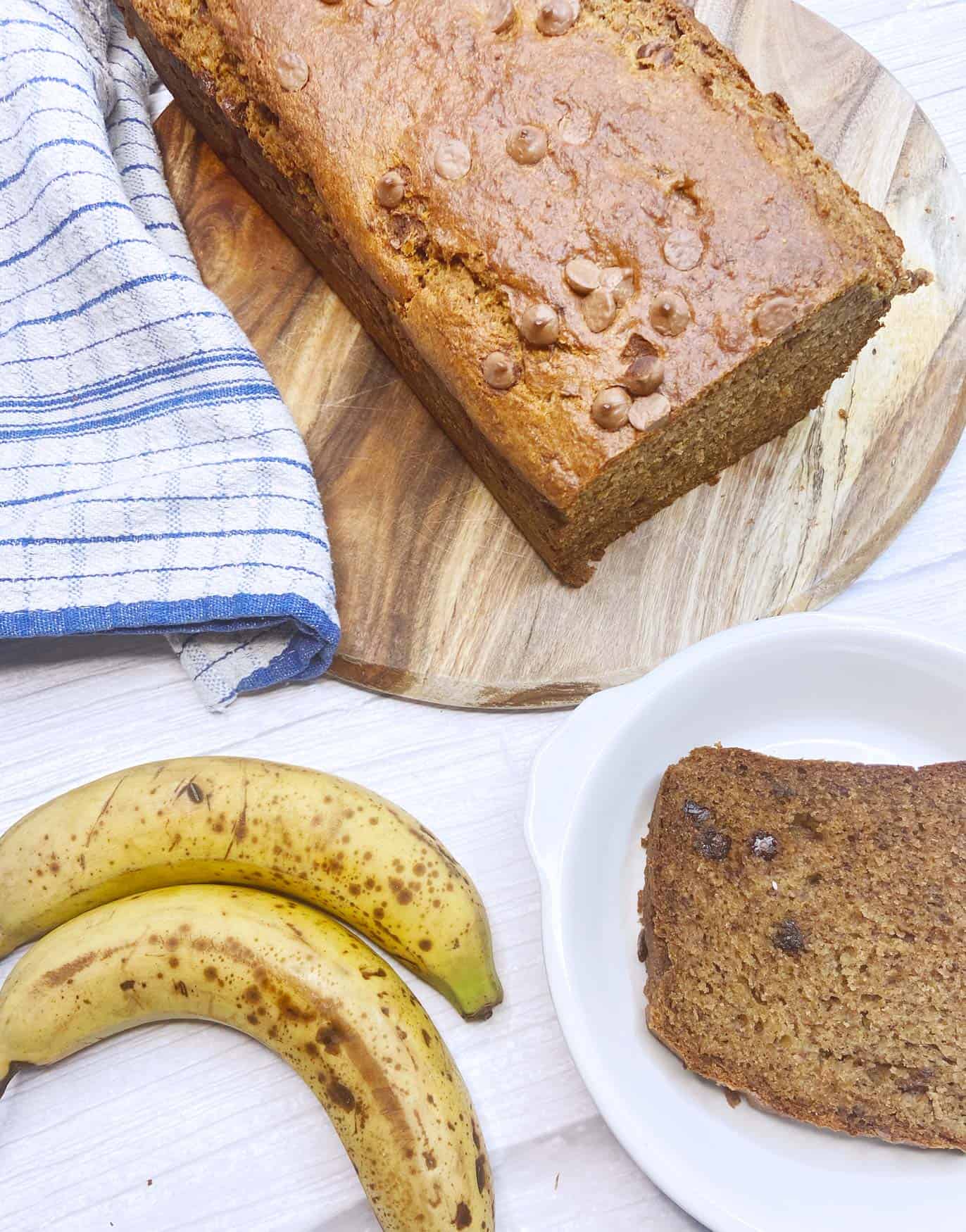 Close up picture of cut banana bread with ripe bananas and banana bread slice
