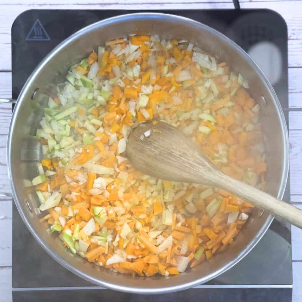 Pot with chopped vegetables and wooden spoon