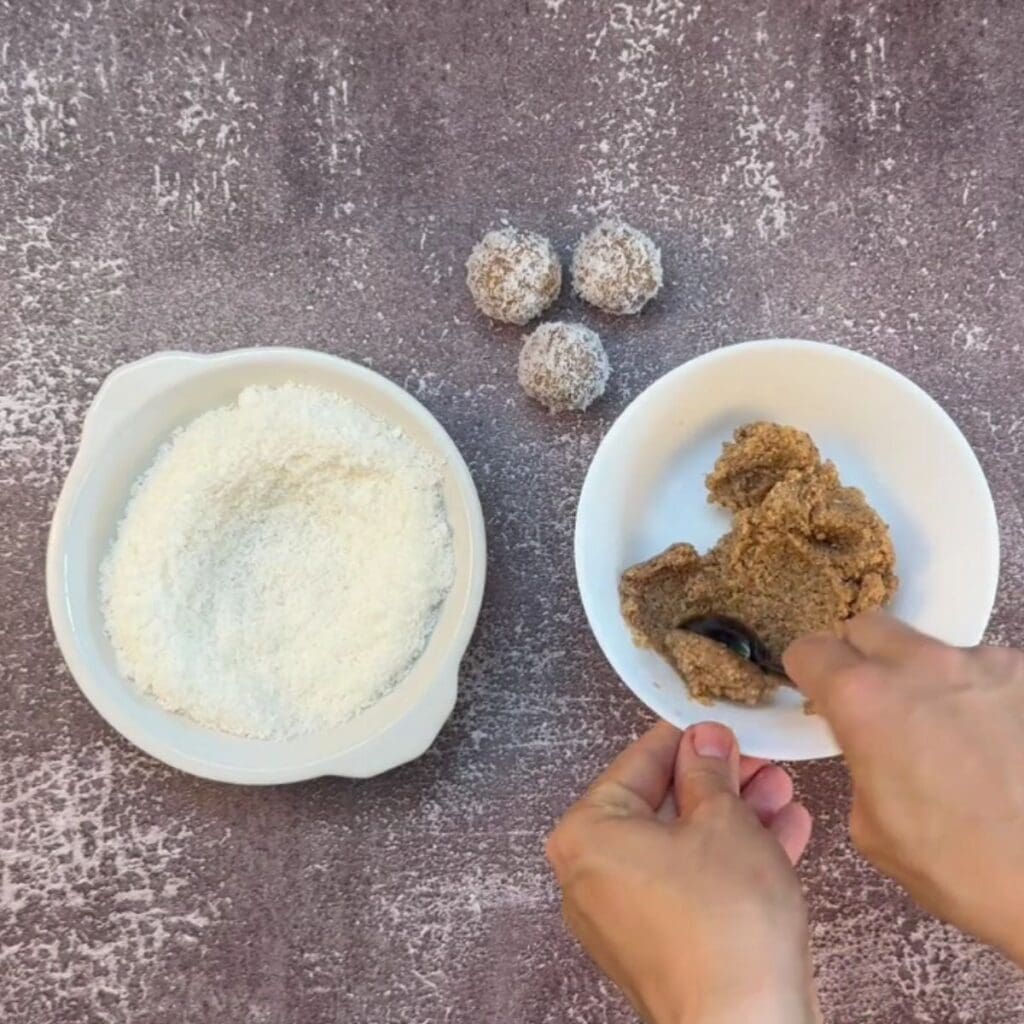 Hand rolling bliss balls and coating them in desiccated coconut