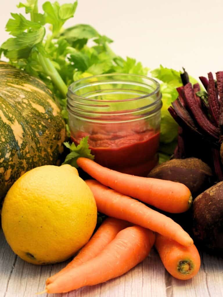 Vertical shot of freshly made nightshade free Nomato Sauce surrounded by its fresh vegetable ingredients